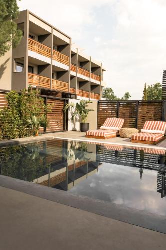 a swimming pool with two lounge chairs next to a building at Cook's Club Ialysos Rhodes in Ialyssos