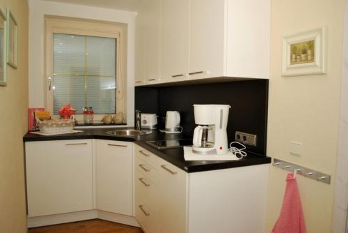 a kitchen with white cabinets and a coffee maker on the counter at Landhaus Notburga in Gries im Sellrain