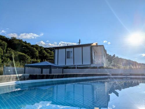 a house with a swimming pool in front of a building at Sunshine Inn Buriani in Buriaki