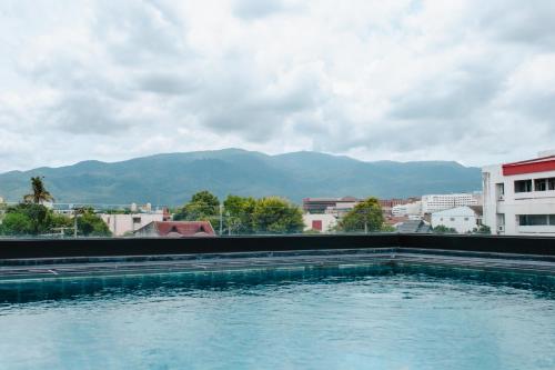 a swimming pool in a city with mountains in the background at NANEE Phra Singh in Chiang Mai