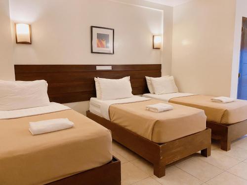 a hotel room with two beds with white sheets at MARZON HOTEL KALIBO in Kalibo