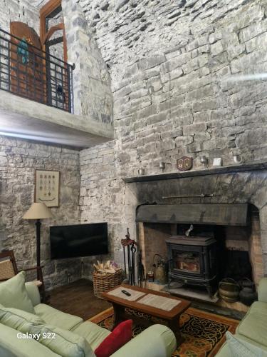 a living room with a stone wall with a fireplace at Ballindooley Castle in Galway