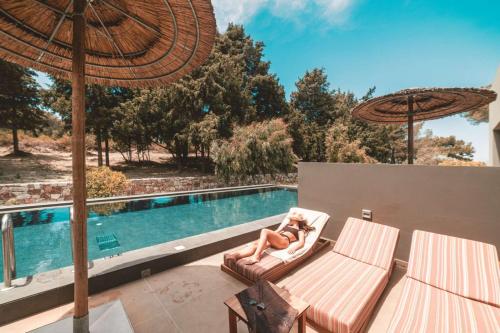 a woman laying on a chair next to a swimming pool at Cook's Club Ialysos Rhodes in Ialyssos