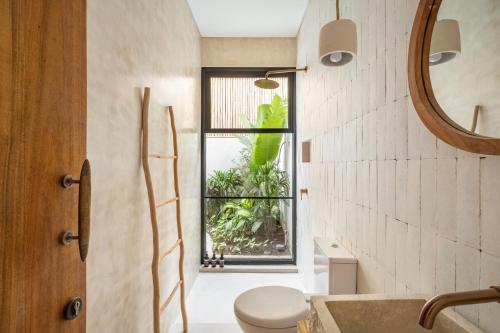 a bathroom with a toilet and a window at Alma Bingin Boutique Hotel in Uluwatu