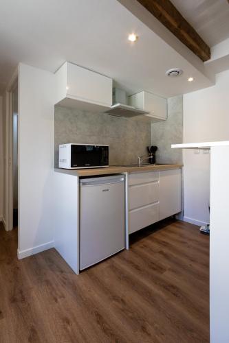 une cuisine avec des armoires blanches et un micro-ondes dans l'établissement Studio Nature Bohème, à Montargis