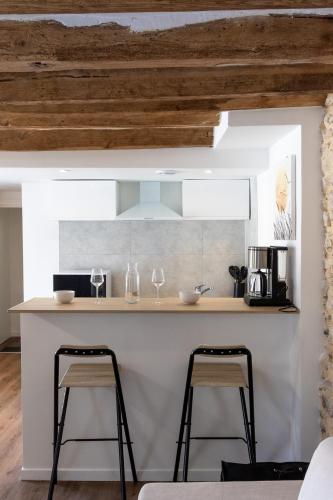 une cuisine avec un comptoir et deux tabourets dans l'établissement Studio Nature Bohème, à Montargis