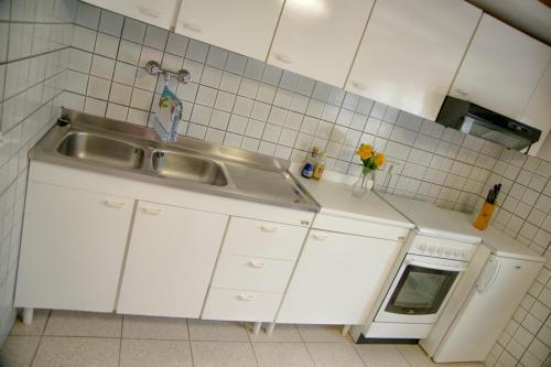 a white kitchen with a sink and a stove at Casa Furrer in Tirrenia