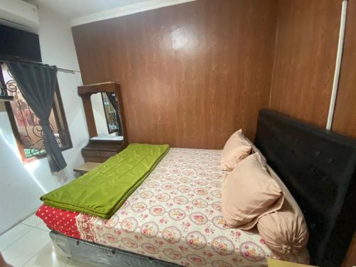 a bed with a green blanket on top of it at Kedyla Homestay Syariah in Ngabean
