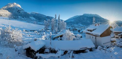 a village covered in snow with a church and mountains at s´Bergnestle in Bad Hindelang