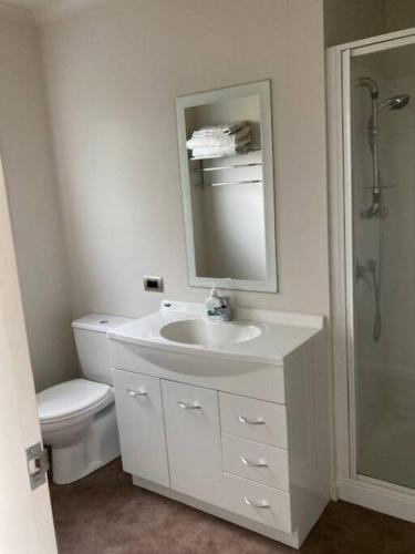 a bathroom with a sink and a toilet and a mirror at The Bach Wai Rua A Waterfront Home in Opononi