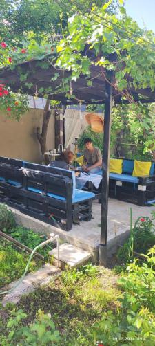 two men sitting on a blue bench under a canopy at Kuki dom Ganja in Bagbanlar