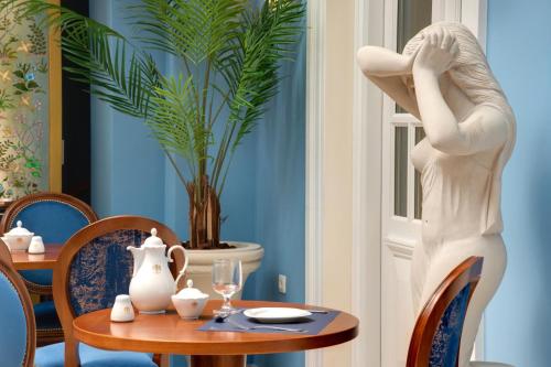 een standbeeld van een vrouw die naast een tafel staat bij Grande Bretagne - Nafplio in Nafplio