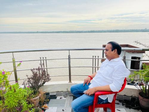a man sitting in a red chair in front of the water at River view paying guest house in Varanasi
