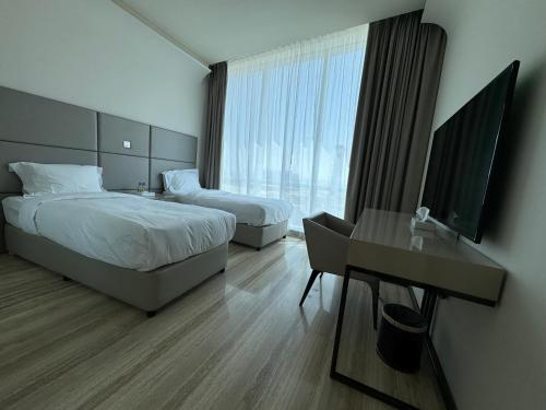 a hotel room with two beds and a desk and a television at DAMAC Towers Riyadh by SELSAL داماك الرياض in Riyadh