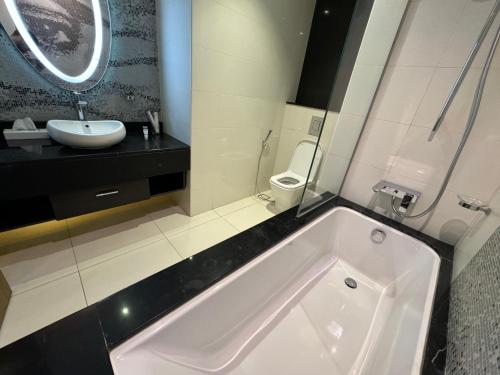 a bathroom with a tub and a sink and a toilet at DAMAC Towers Riyadh by SELSAL داماك الرياض in Riyadh