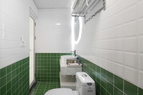 a green and white bathroom with a toilet and a sink at King'sLandind BnB in Chongqing