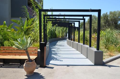 a walkway with a bench next to a building at Cook's Club Ialysos Rhodes in Ialyssos
