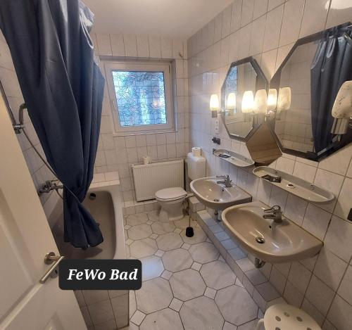 a bathroom with two sinks and a toilet and a mirror at Landgasthof "Hotel zum Norden" in Jagel