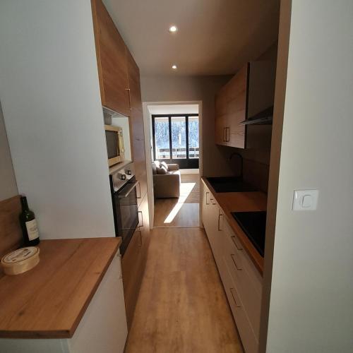 une cuisine avec des placards en bois et un salon dans l'établissement Appartement osca des brimbelles, à La Bresse