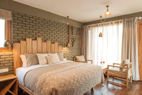 Un dormitorio con una cama grande con una pared de ladrillo. en The Birdcage, Mukteshwar, en Mukteshwar