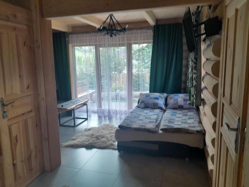 ein Schlafzimmer mit einem Bett und einem großen Fenster in der Unterkunft Domki Harenda in Zakopane