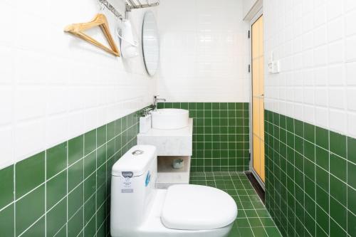 a green tiled bathroom with a toilet and a sink at King'sLandind BnB in Chongqing
