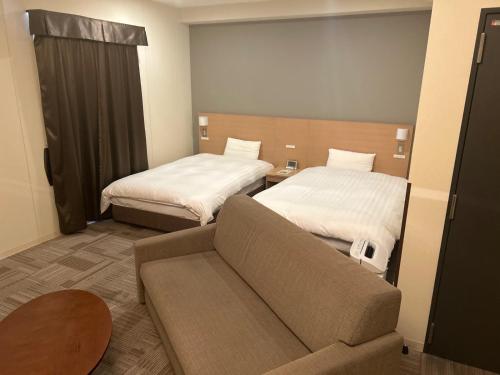 a living room with two beds and a couch at Dormy Inn Express Koriyama in Koriyama