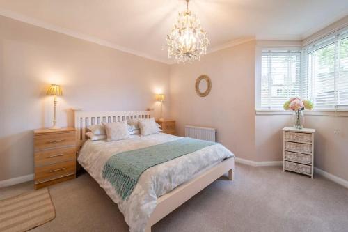 a bedroom with a large bed and a chandelier at Immaculate City Centre Apartment with Free Parking - Ground Floor in Aberdeen
