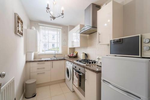 a kitchen with a stove and a refrigerator at Immaculate City Centre Apartment with Free Parking - Ground Floor in Aberdeen