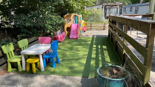 a yard with chairs and a table and a playground at SAYANG26 gezellige gezinsvriendelijke stacaravan op familiecamping De Vossenburcht in natuurgebied Reestdal - no workers allowed in IJhorst