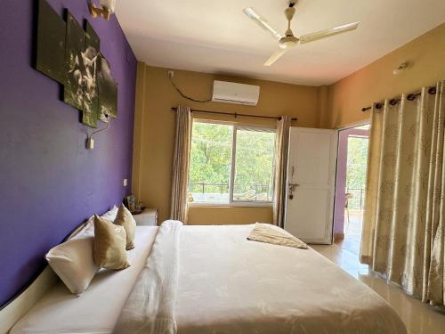 a bedroom with a white bed with a purple wall at Hotel Rhinoceros-Homestay in Sauraha