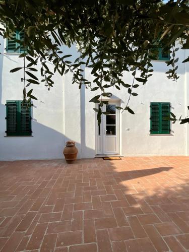 a white building with green shuttered windows and a tree at Casa vacanze Eny in Capannori