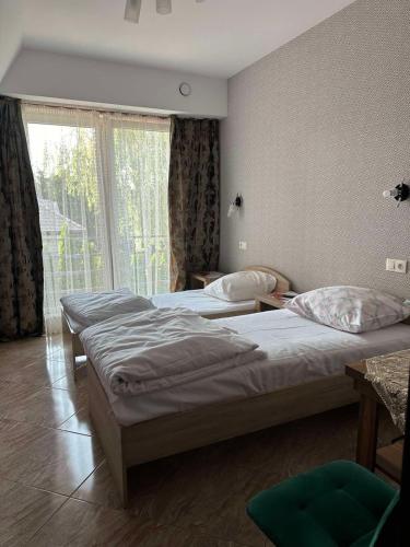 a bedroom with three beds and a large window at Villa Speranza Kościelna Droga 12 in Łomianki Dolne