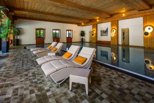 a pool with several lounge chairs and a swimming pool at Alm- & Wellnesshotel Alpenhof in Schönau am Königssee