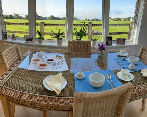 a dining room with a table with a view of a field at Brooklands in Tavistock