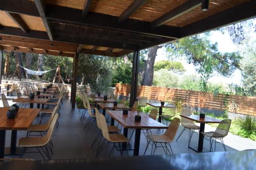 a restaurant with wooden tables and chairs and trees at Cook's Club Ialysos Rhodes in Ialyssos