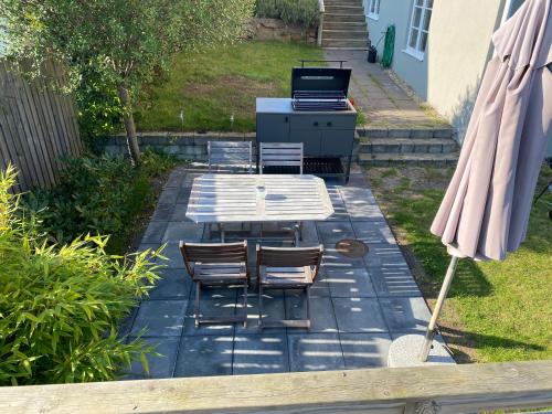 a patio with a table and chairs and a grill at Solhyddan, tvårumslägenhet i villa nära havet in Båstad