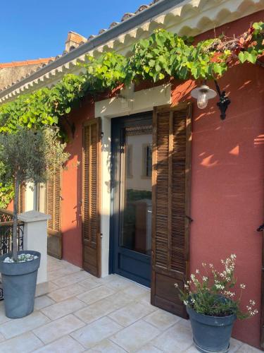a red house with a blue door and some plants at La Maison Clémenceau in Salon-de-Provence