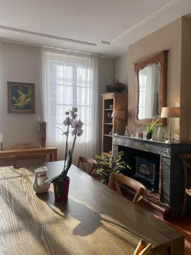 a living room with a table and a fireplace at La Maison Reverdi in Lamarque
