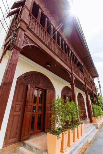 a building with a large wooden door and some plants at The Artist - Fong Lee CC Lampang Walking Street in Lampang