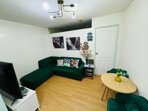 a living room with a green couch and a table at Condo in Marilao with Free Videoke in Marilao
