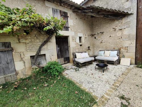 un patio avec deux chaises et une table devant un bâtiment dans l'établissement Studio Confortable à Civaux A proximité Poitiers, à Cubord