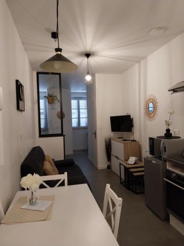 a living room with a white table and a kitchen at Le Coeur de Sel in Salins-les-Bains