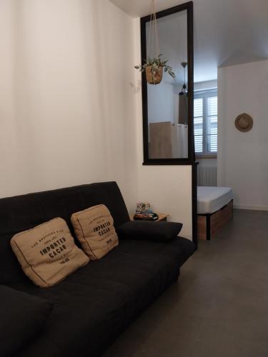 a black couch in a living room with a mirror at Le Coeur de Sel in Salins-les-Bains