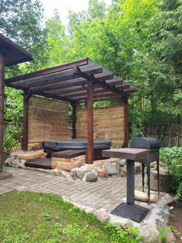 a wooden pergola with a picnic table and a bench at LejasVāgneris in Tukums