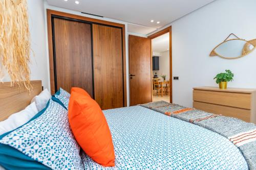 Schlafzimmer mit einem Bett mit orangefarbenen und blauen Kissen in der Unterkunft Welcome Home Palmiers in Casablanca
