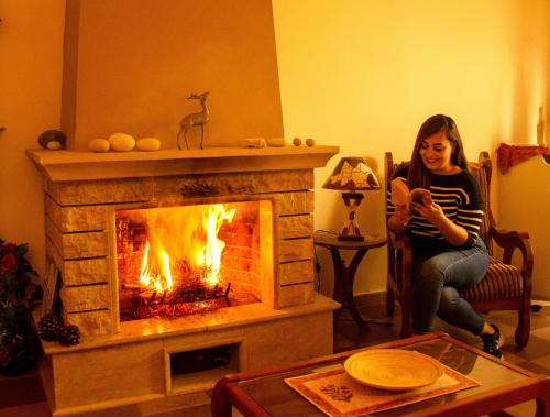 a woman sitting in a chair in front of a fireplace at The Ranch in Kfar Hazîr