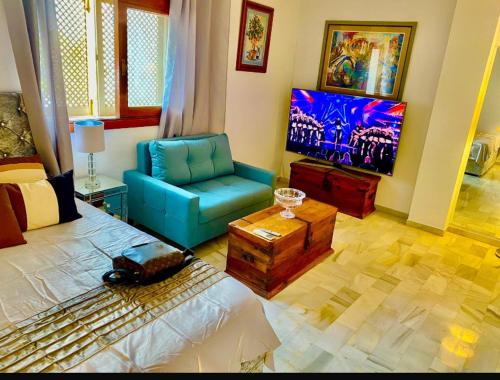 a living room with a bed and a blue chair at Stunning suite at Hotel Del Golf, 5 stars and frontline Golf, Porto Banus, Marbella in Marbella