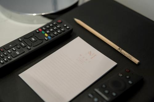 a pen and a piece of paper next to a remote control at Mert Boutique Hotel in Korçë