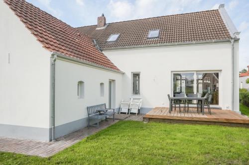 a white house with a deck and a table at Friesenhus - Jever in Jever